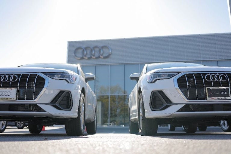 Two Audi sedans parked in front of dealership