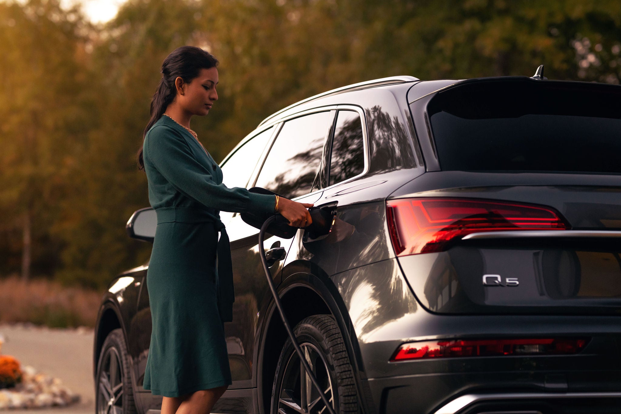 Side profile of a woman beside an Audi Q5 PHEV.