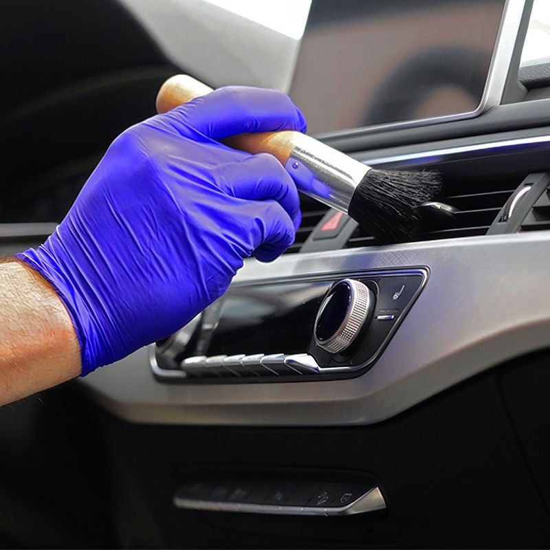A close up image of a gloved hand brushing the dask of an Audi 