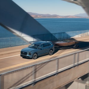 Side view of the Audi Q7 towing a boat while accelerating on a bridge.
