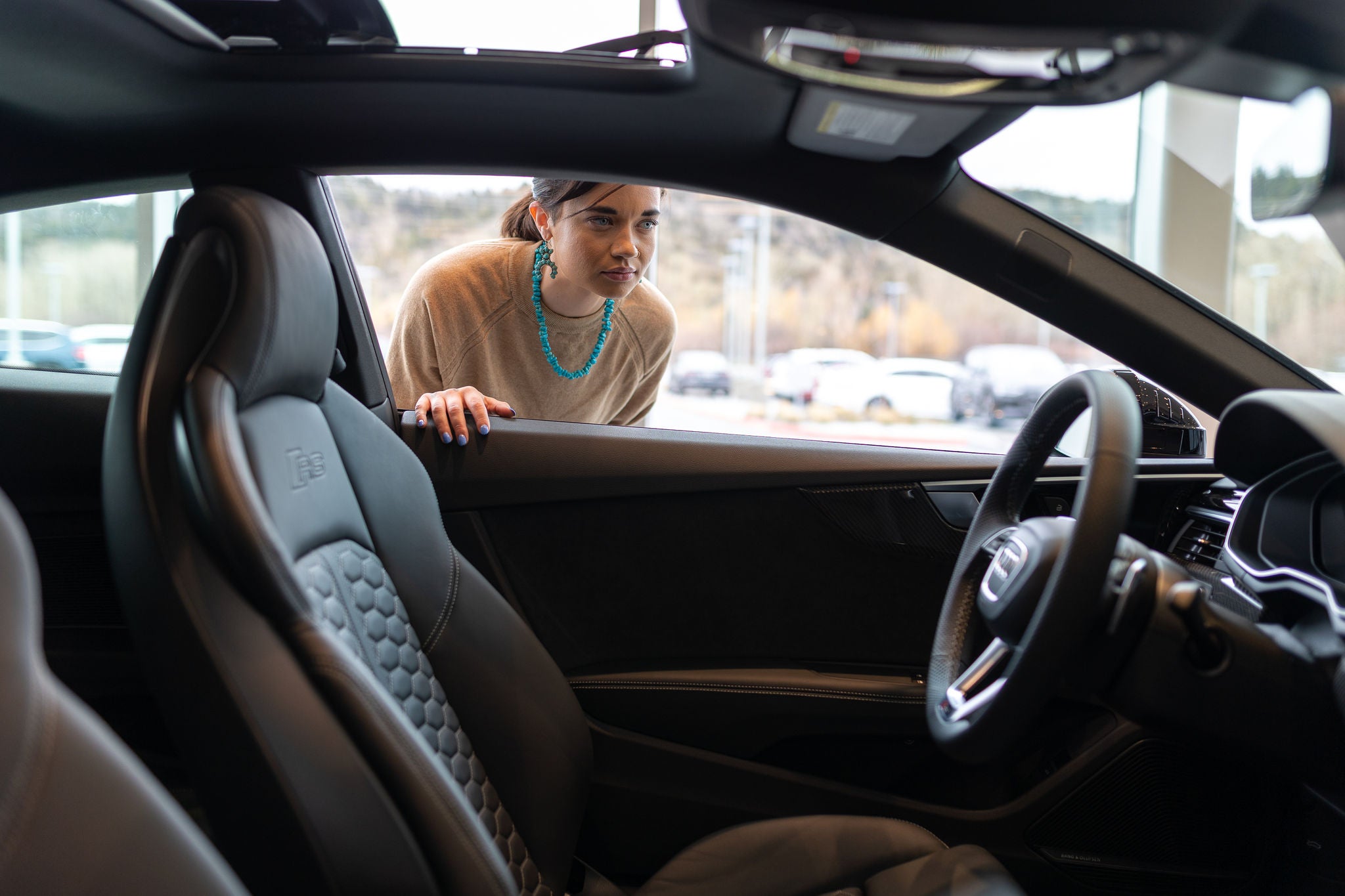 Woman looking inside Audi vehicle. 