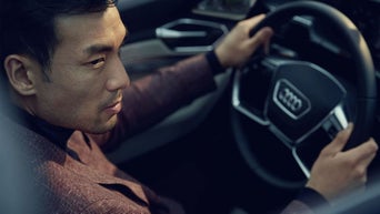 Over-the-shoulder key of a person sitting in the driver's cockpit of an Audi vehicle.