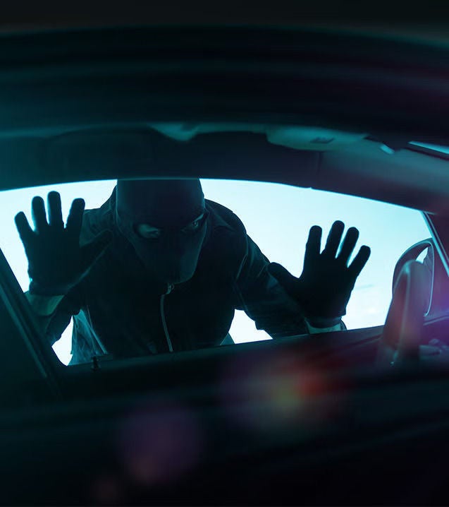 Image of a thief looking into a vehicle through the driver window