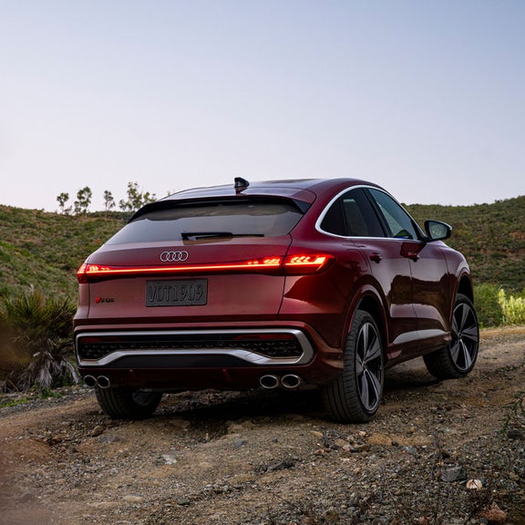 Three-quarter rear view of an Audi SQ5 parked on a gravel surface.