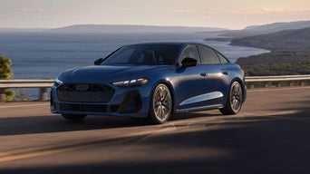 Three-quarter front view of the Audi S5 accelerating on an oceanside road.