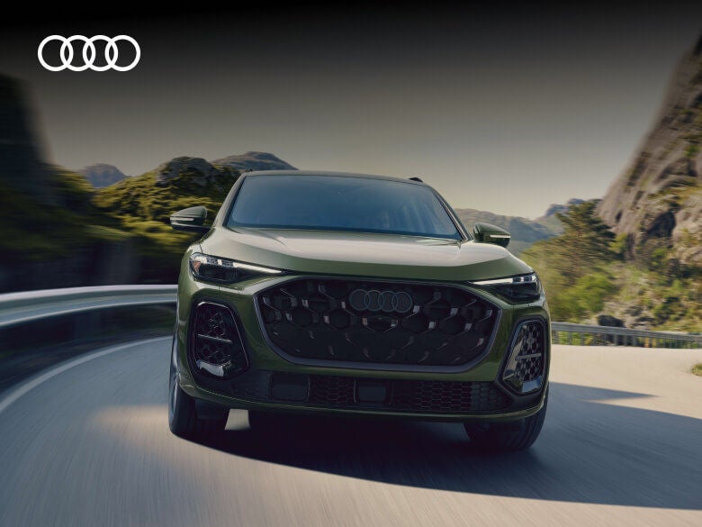 Front view of a green Audi Q5 driving along a winding mountain road.
