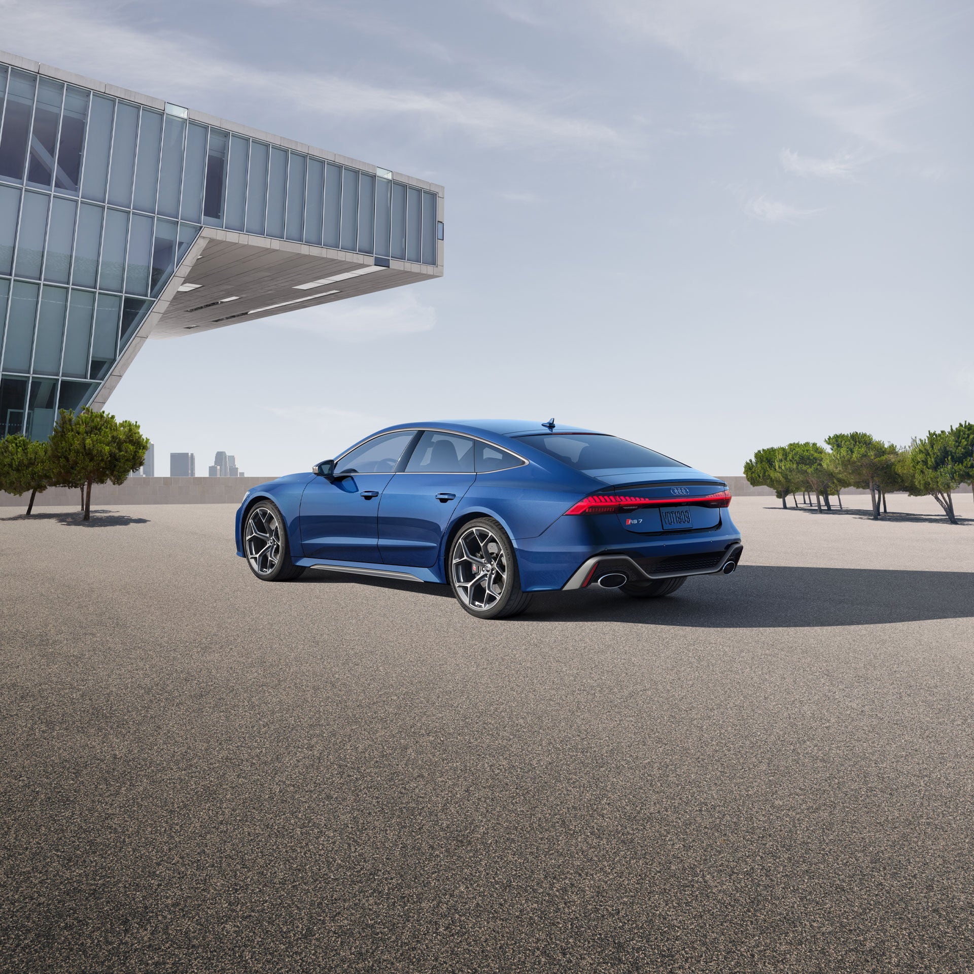 Three-quarter rear view of the Audi RS 7 performance parked next to a modern building.