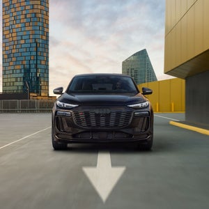 Front profile view of the Audi SQ6 Sportback e-tron accelerating, showing the daytime running lights on the headlights.