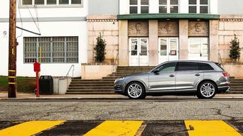 Side profile view of an Audi vehicle parked in front of a building.