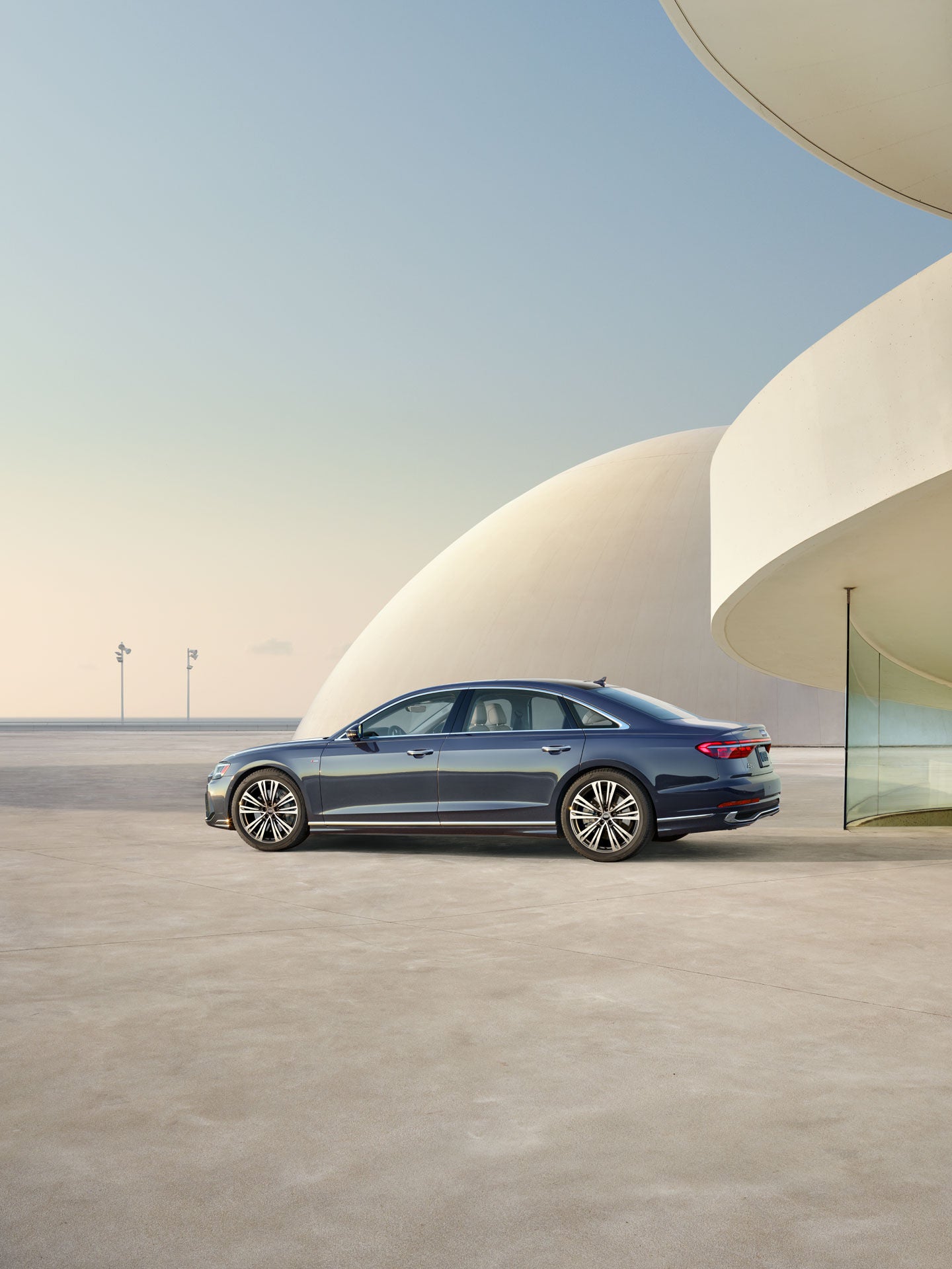 Side profile of the Audi A8 parked by a futuristic building.