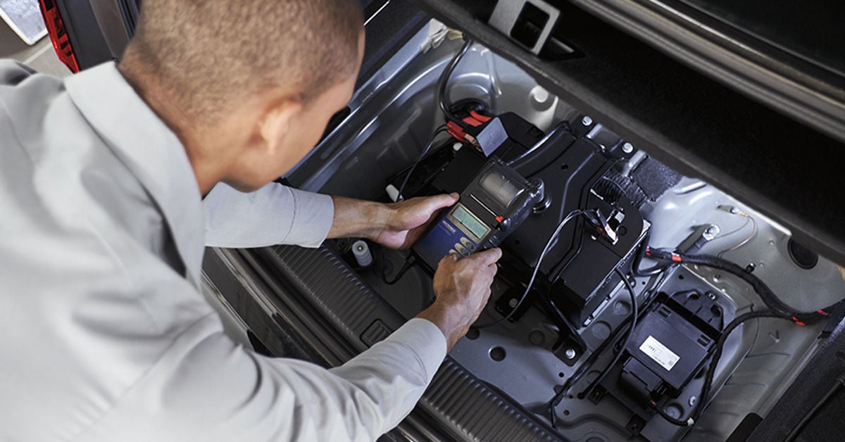 Genuine Audi parts technician installing a battery