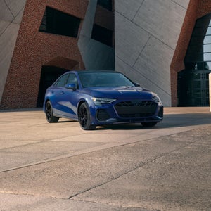 An Audi A3 parked in front of a modern building.