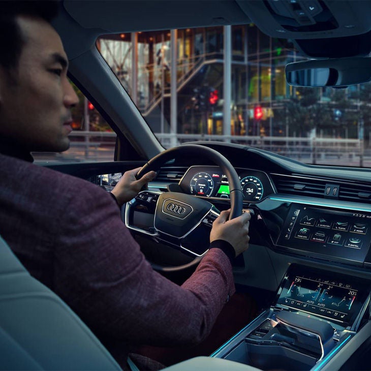 Side profile of a man driving on a city street in his Audi.
