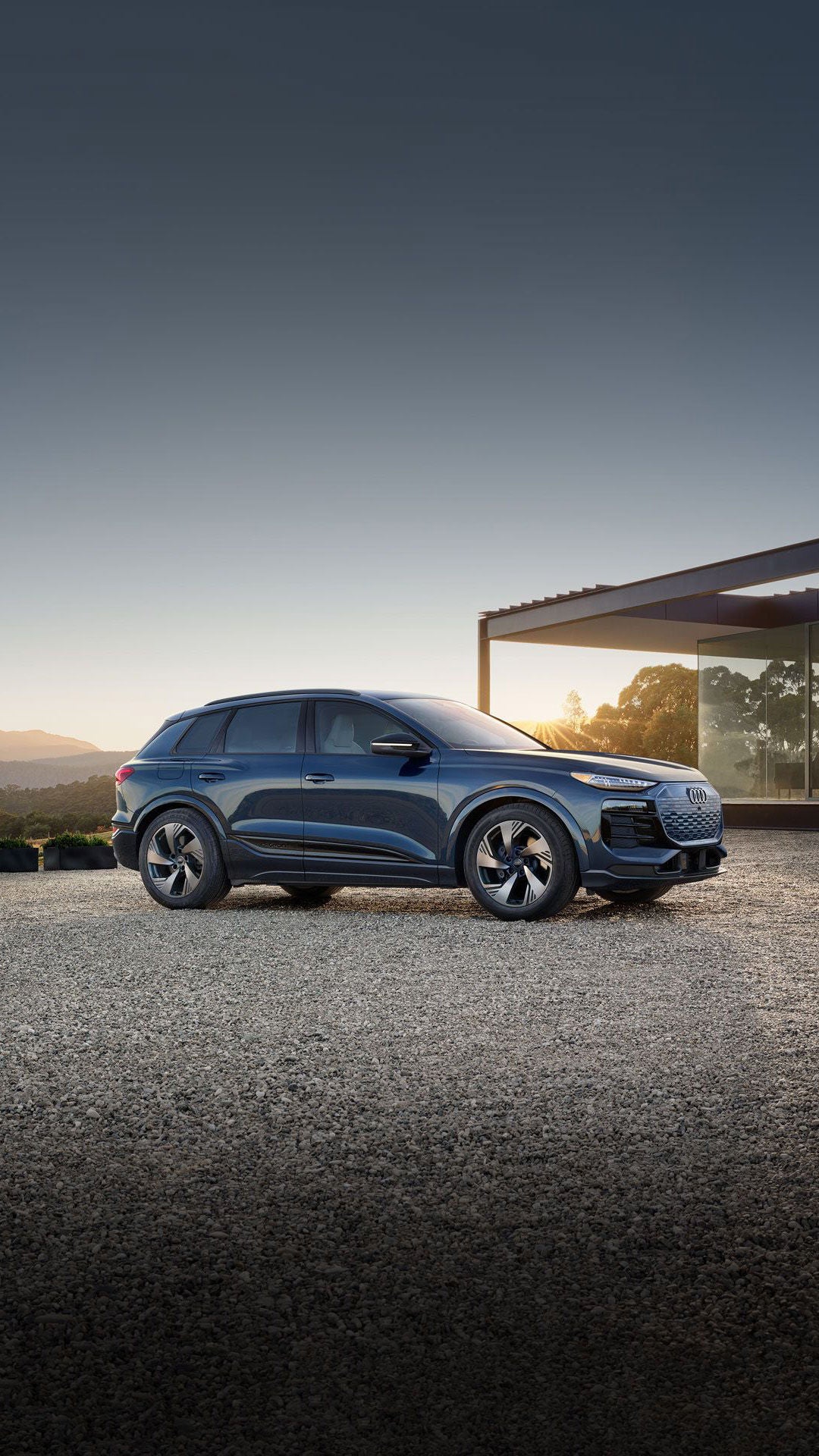 Side profile shot of the 2025 Audi Q6 e-tron parked in front of modern home.