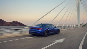 Three-quarter front view of a dark silver Audi RS 6 in motion.  