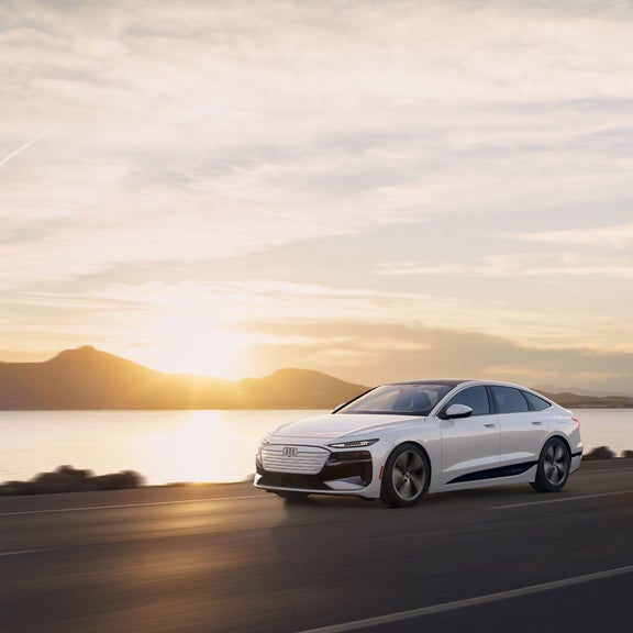 Side view of the Audi A6 Sportback e-tron accelerating next to a body of water.