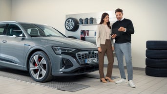 An Audi dealer discussing maintenance requirements with an Audi owner at the dealership.