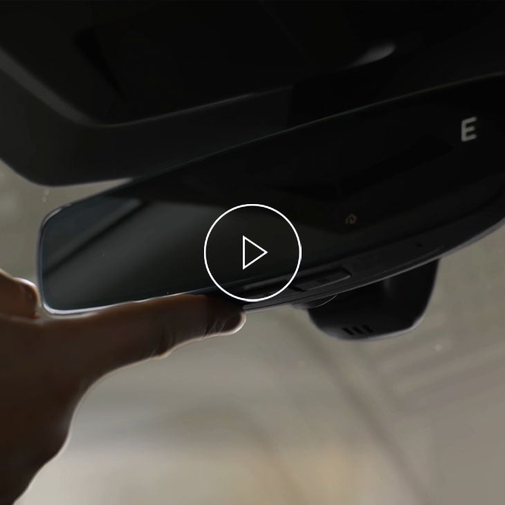 A person pressing the homelink button on their rearview mirror.