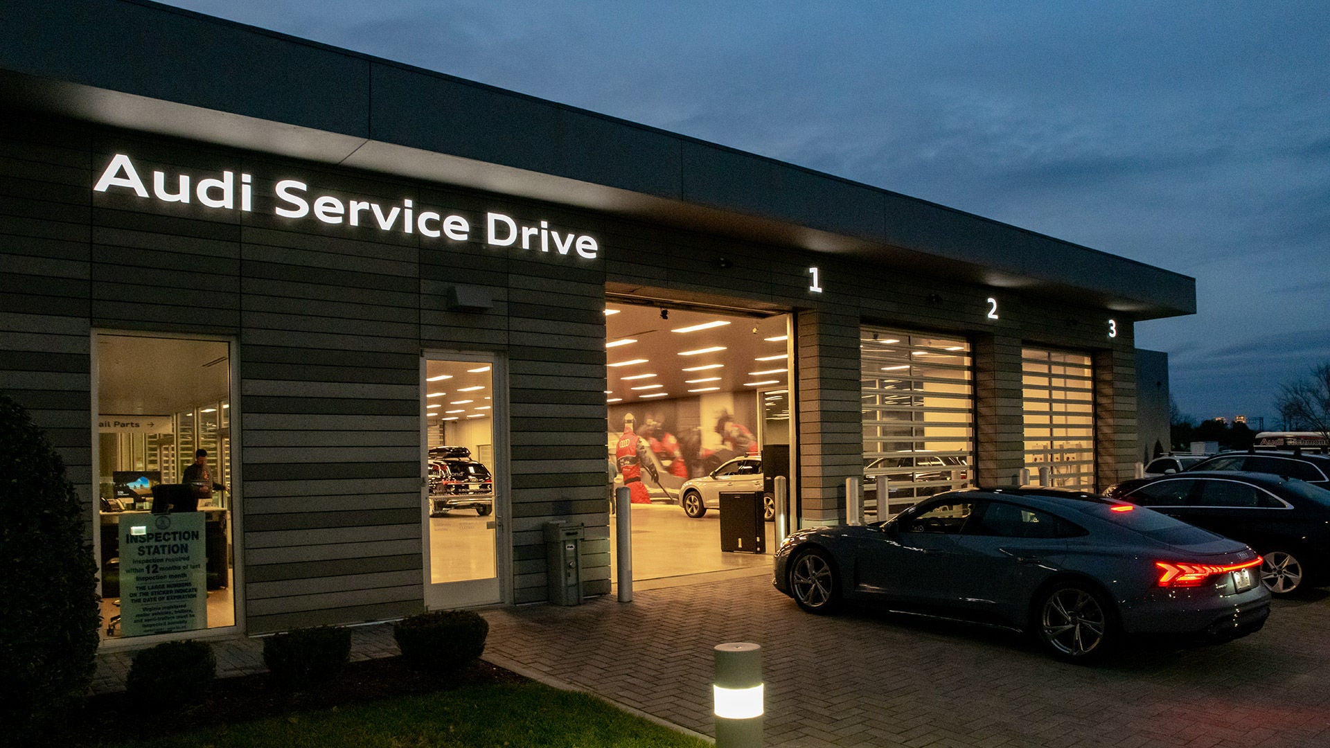3/4 side profile of the Audi Q6 e-tron parked next to a modern house.