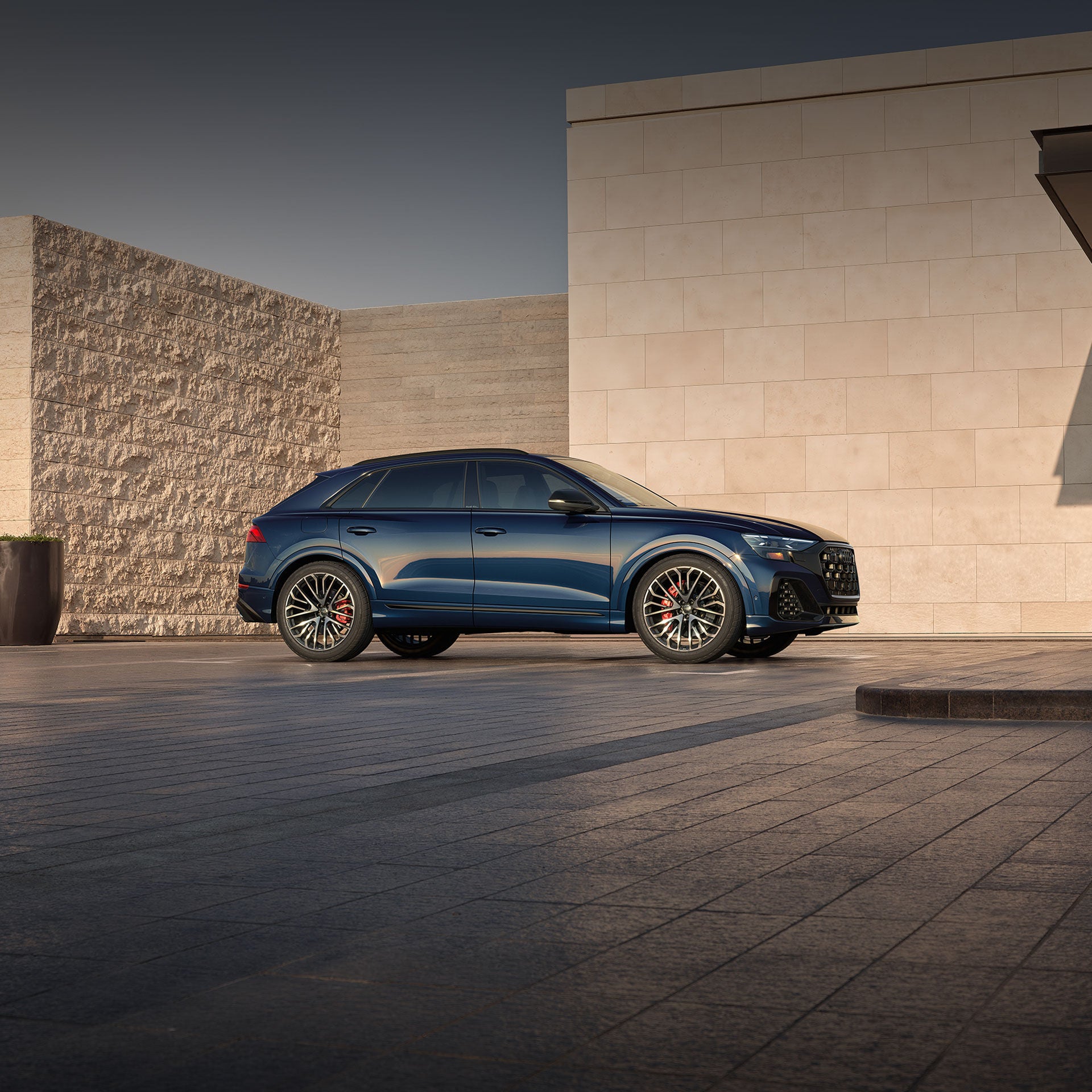 Side profile of the Audi SQ8 parked by a modern home.