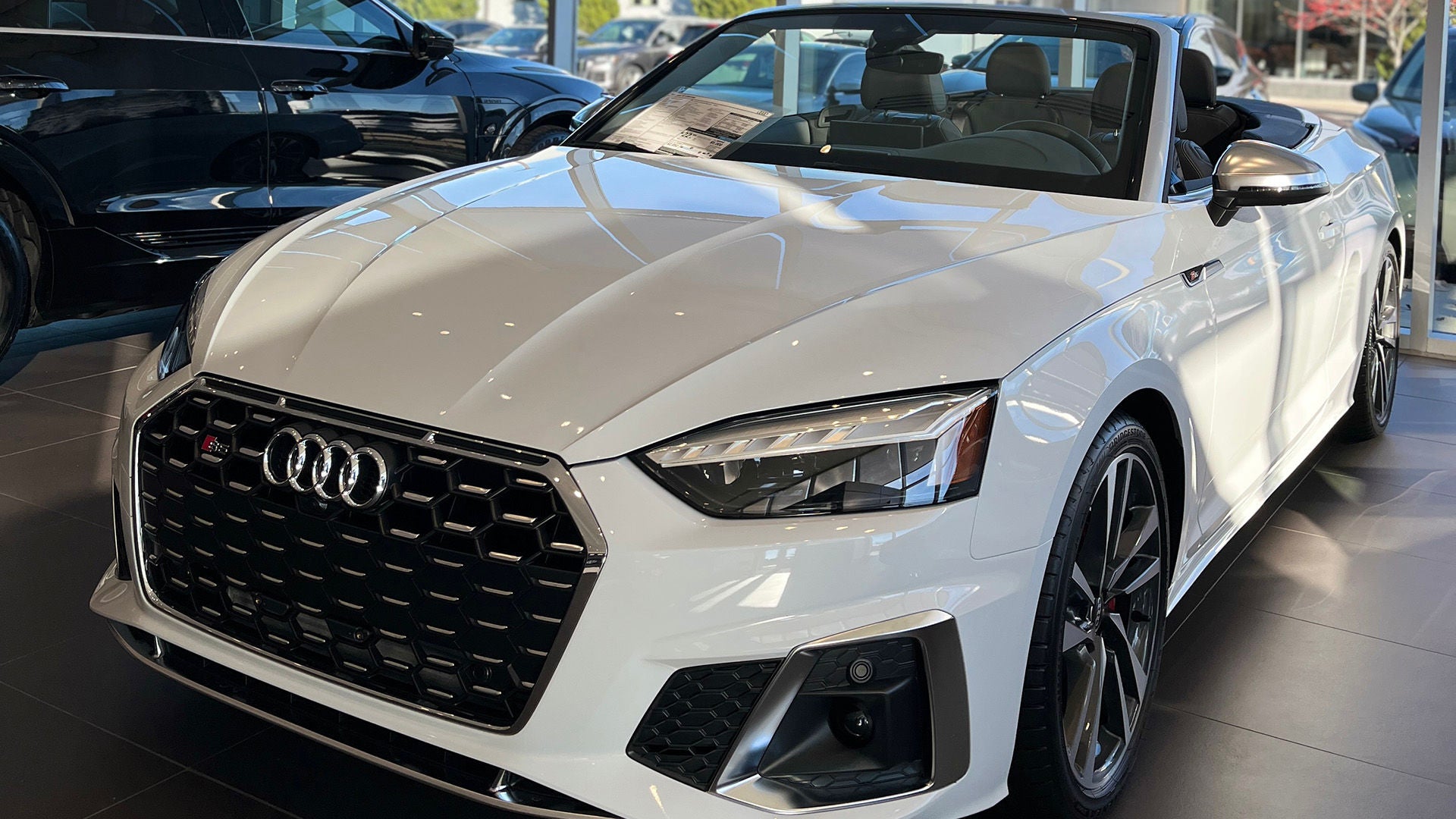 Three quarter view of a white Audi vehicle parked inside showroom