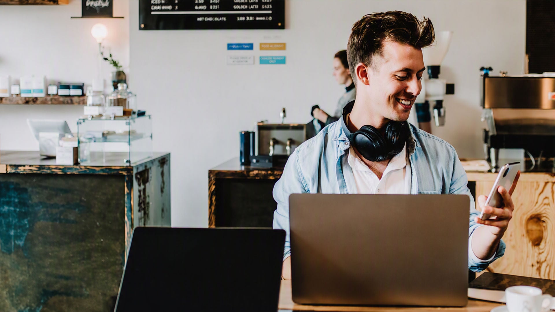 Man smiling at phone while working on laptop
