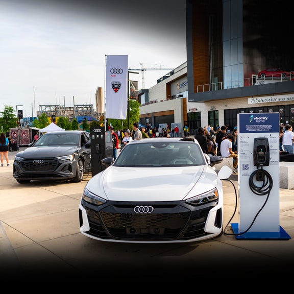 A white Audi e-tron GT hooked up to a charging station outside of Audi Field.