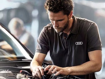 Service technician servicing vehicle with hood open.