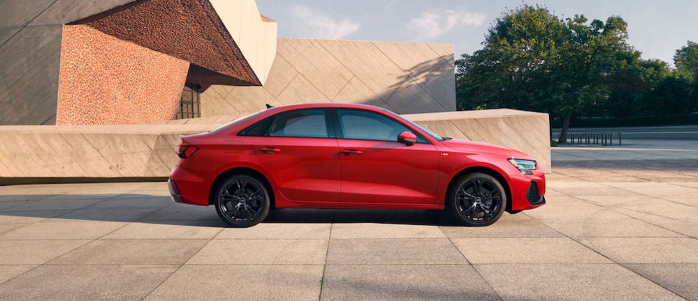 A red 2026 Audi A3 sedan parked in front of a modern, angular building