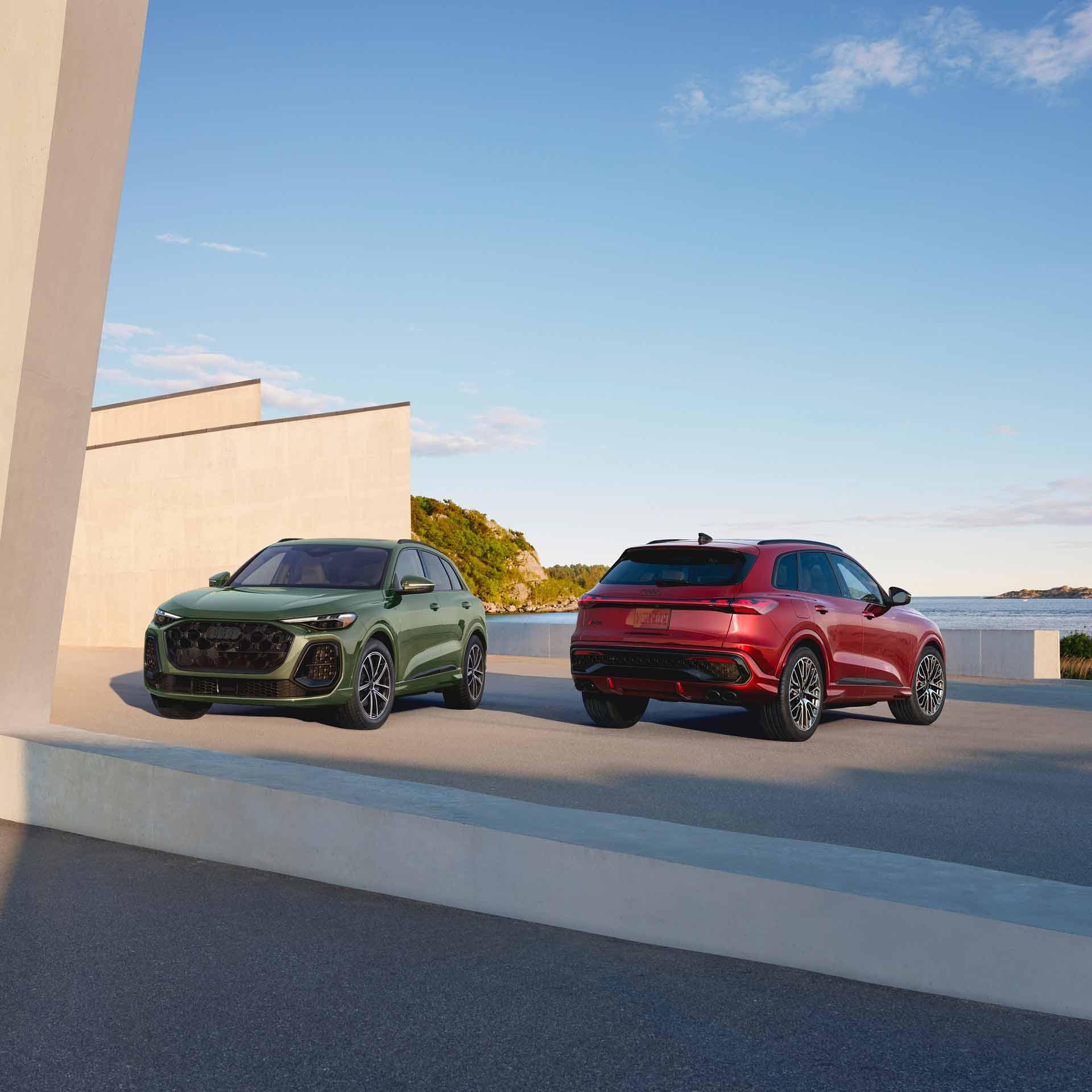 Two Audi Q5 SUVs side by side the left facing towards camera the right facing away, lit from the right.