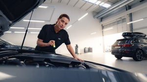 Service technician looking under the hood of an Audi vehicle.