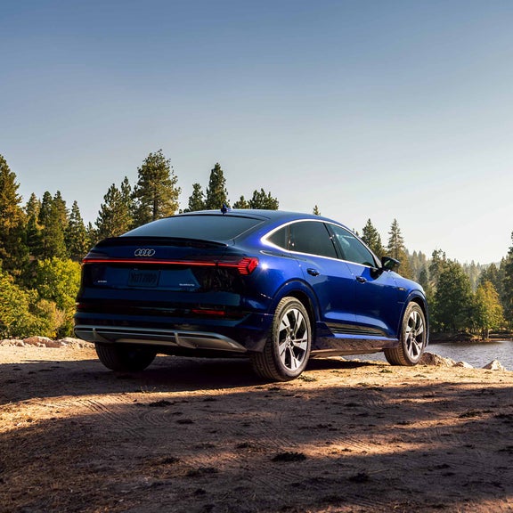 Photo of an Audi e-tron quattro parked next to a serene lake in the woods.