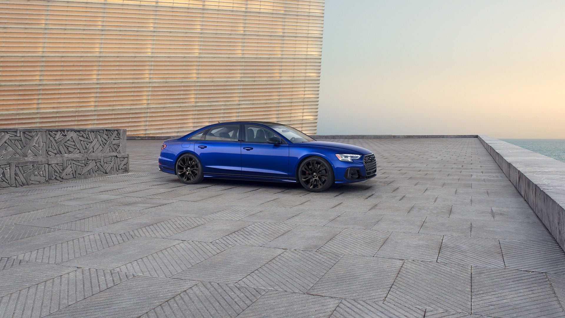 Blue Audi S8 parked on concrete outside, near a body of water.  