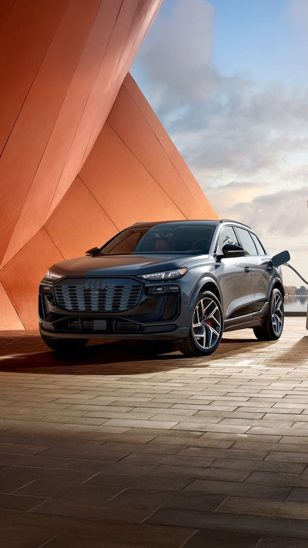 Three-quarter front view of the Audi SQ6 e-tron parked and charging.