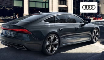  Side view of a 2024 Audi A7 driving along a scenic route near Dayton, showcasing its aerodynamic fastback profile. 