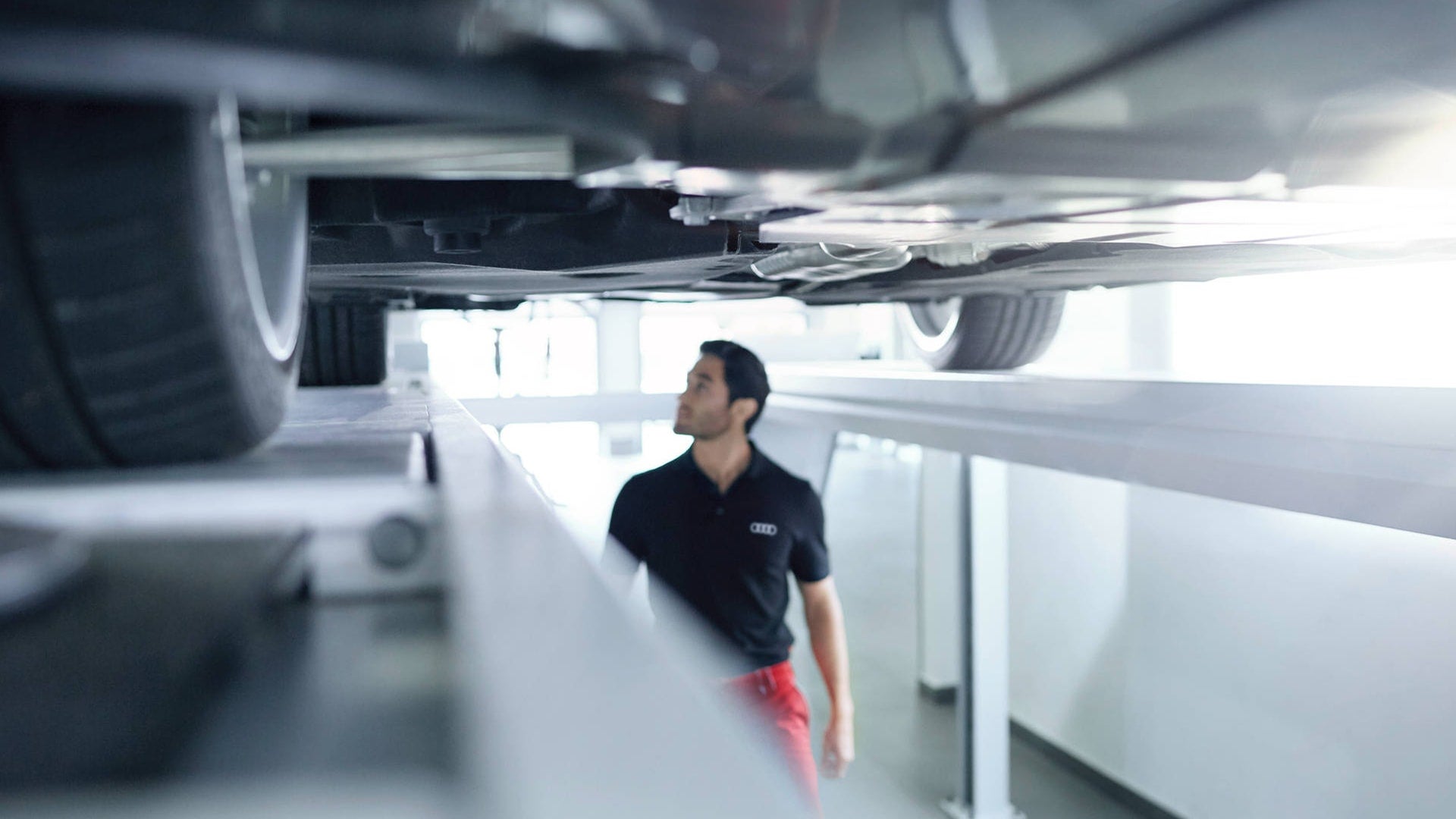 Audi mechanic looking underneath a vehicle.