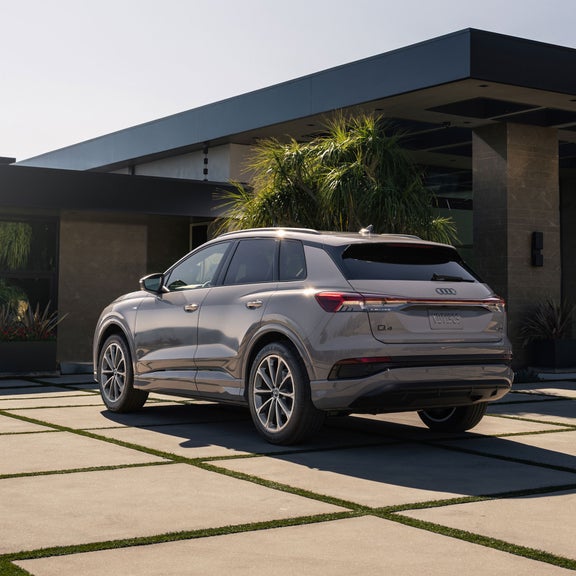 Three-quarter rear view of the Audi Q4 e-tron parked in front of a modern home.