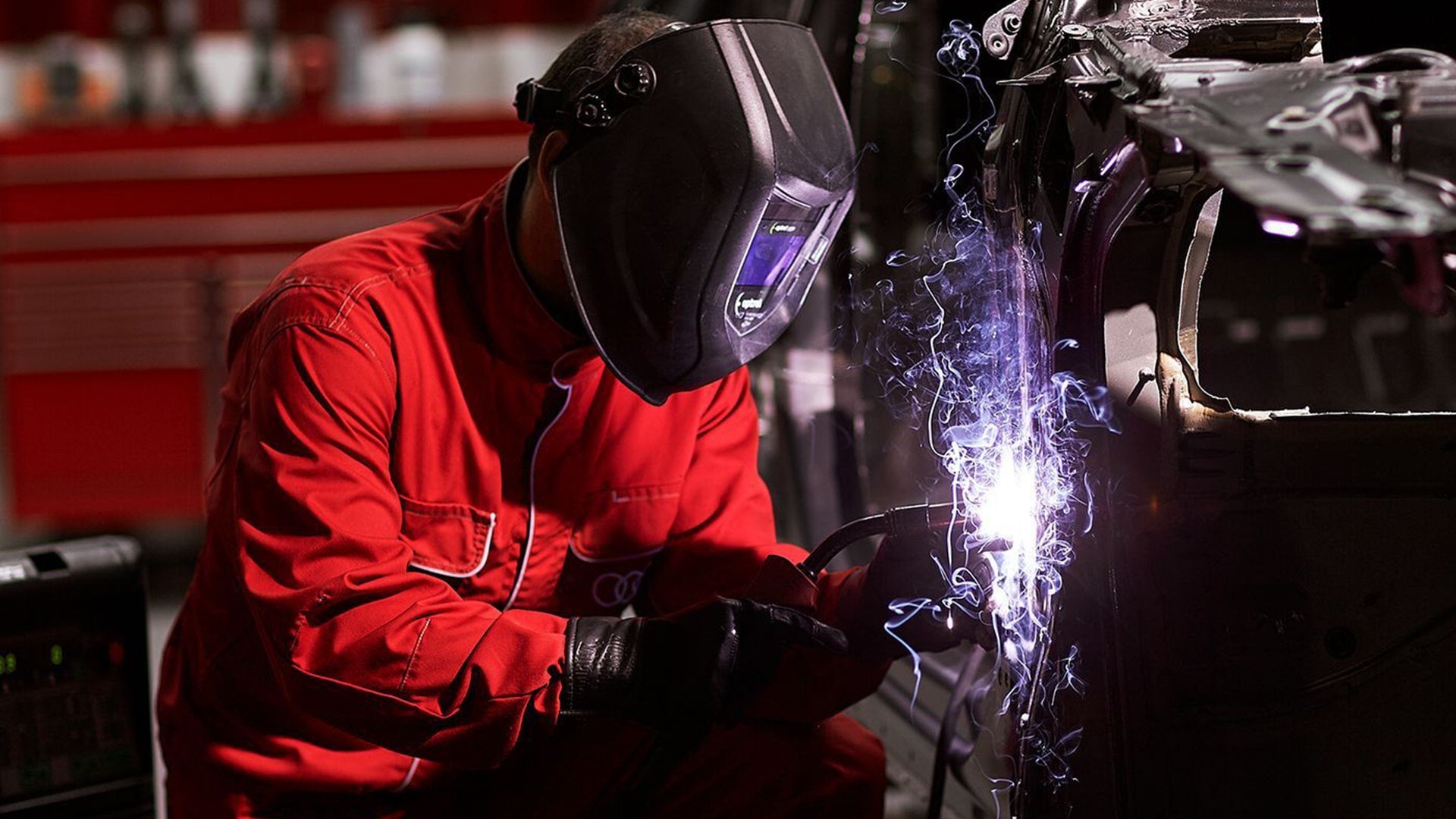 An Audi technician using a welding machine on an Audi vehicle.