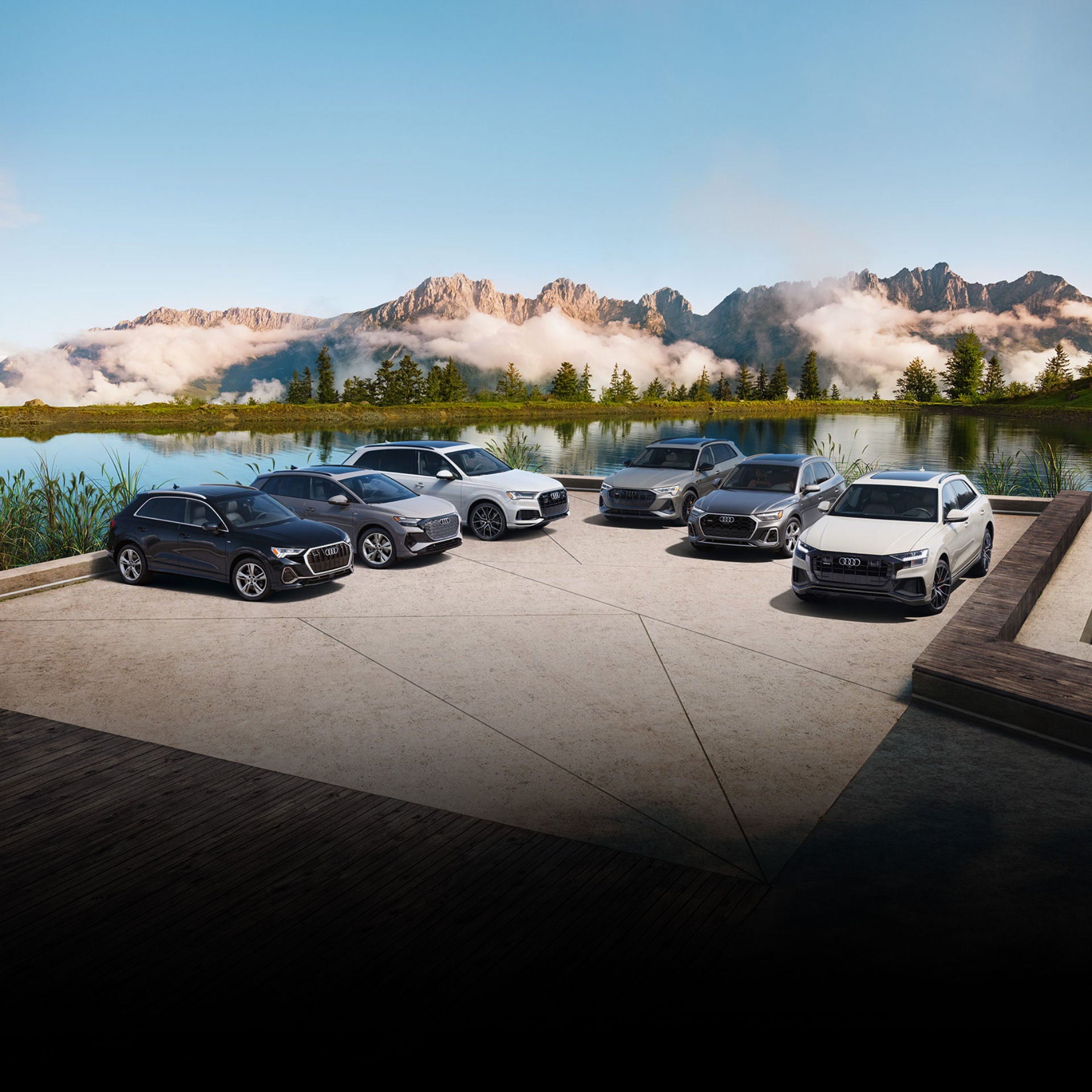 Aerial view of a group of Audi models parked beside a mountain lake.