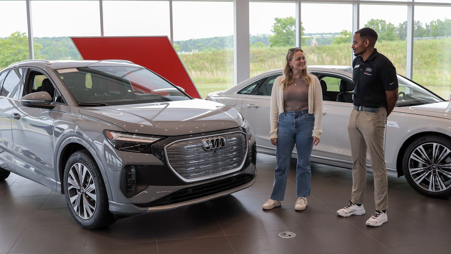 An employee showing a customer cars inside the showroom.