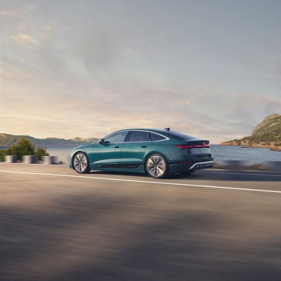 Side view of the Audi S6 e-tron accelerating on a seaside road.