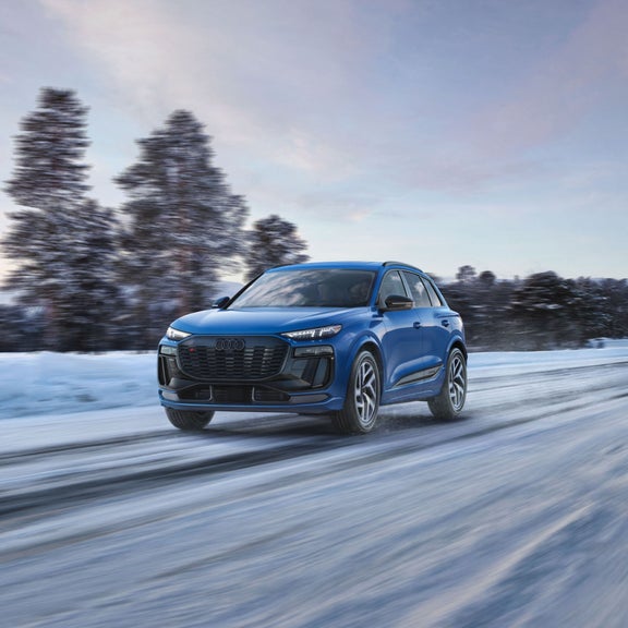 Three-quarter front view of an Audi vehicle accelerating on a snowy road.