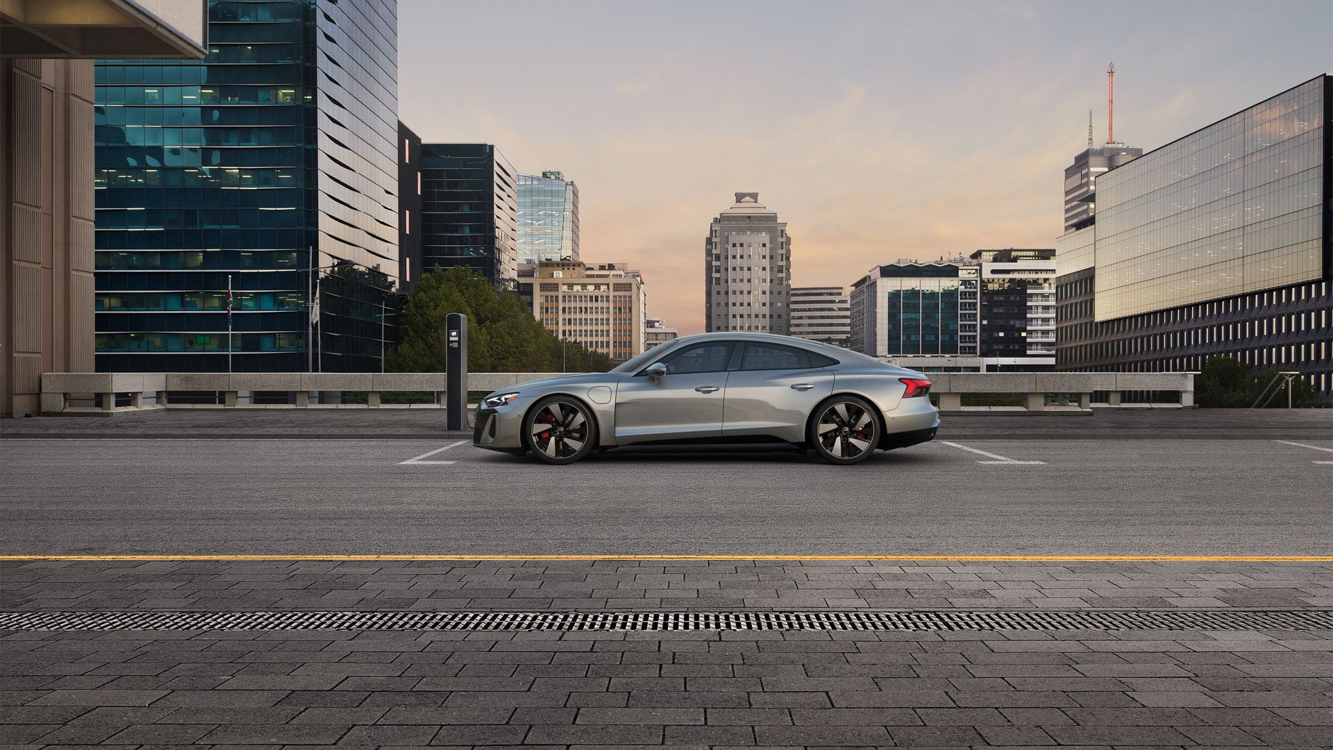 Profil latéral de l'Audi RS e-tron GT garée et en charge sur une route de la ville.
