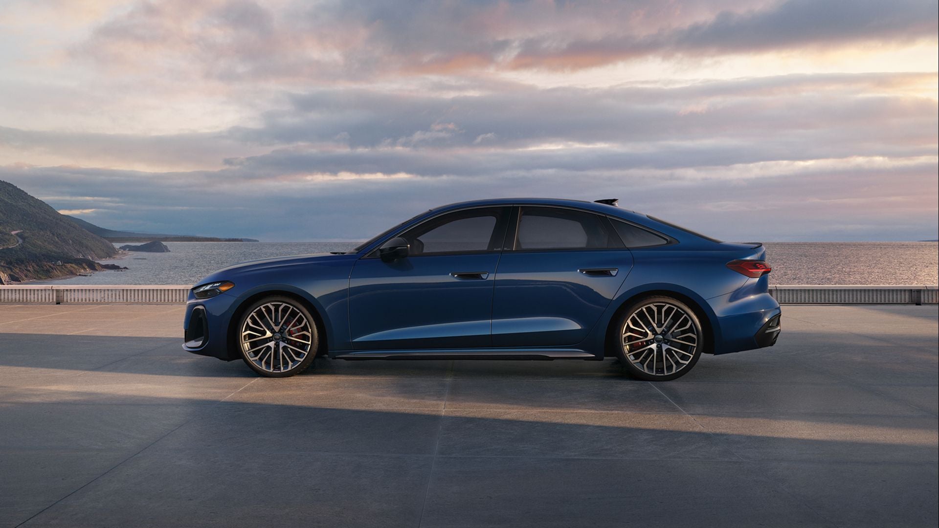 Dark blue Audi S5 Premium Plus parked overlooking a sunset with purple clouds