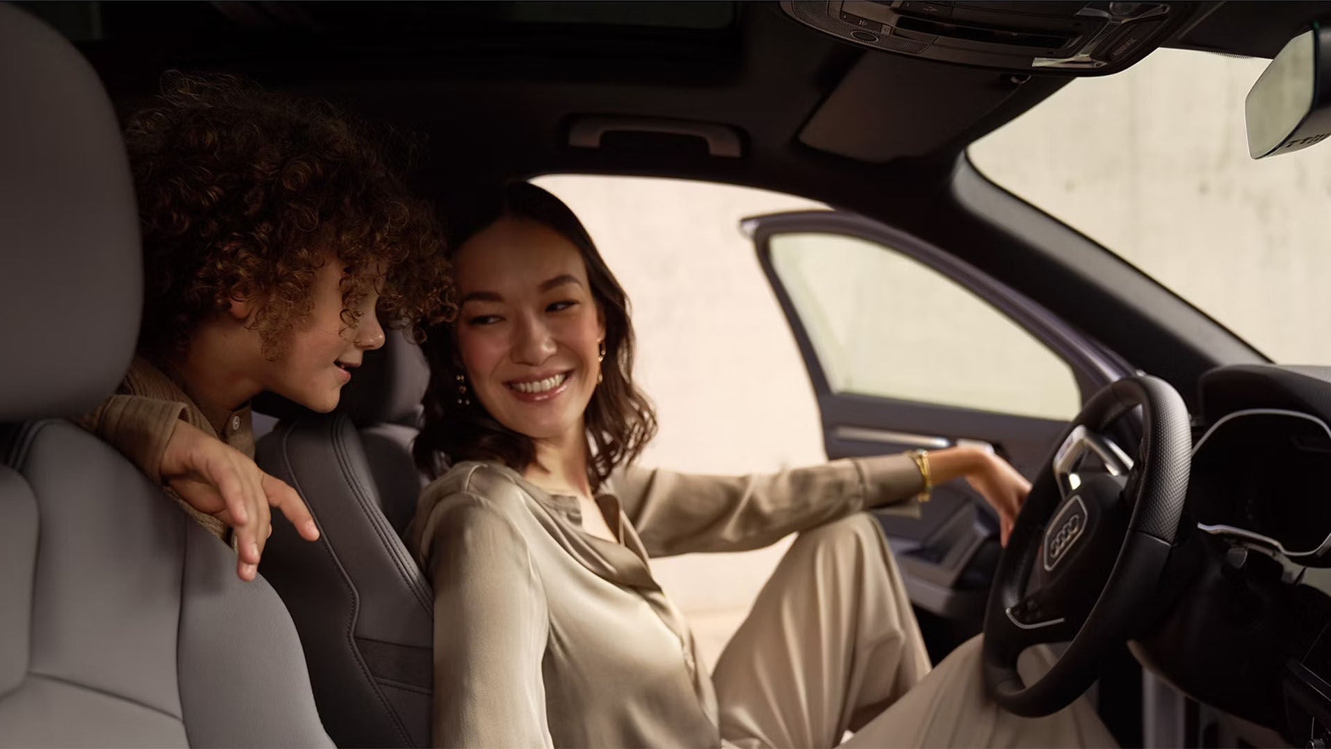 A Woman in the front seat of a car, happy with a child in the back seat
