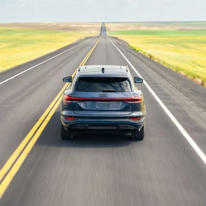 Three-quarter rear view of the Audi Q6 e-tron, parked and charging.
