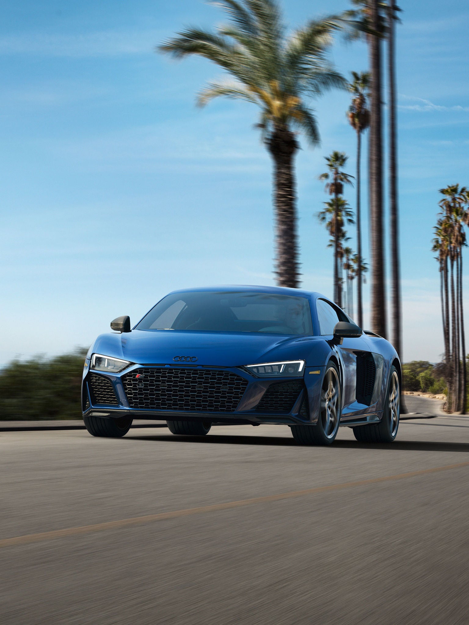 Three-quarter front profile of the Audi R8 Coupe accelerating.