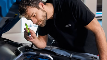 Audi tech inspecting a battery in a vehicle. 