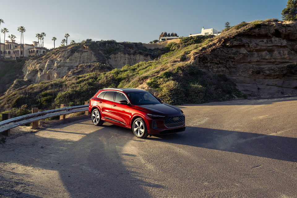 Red Audi Q5 outside on a dirt road with mountains behind it. 