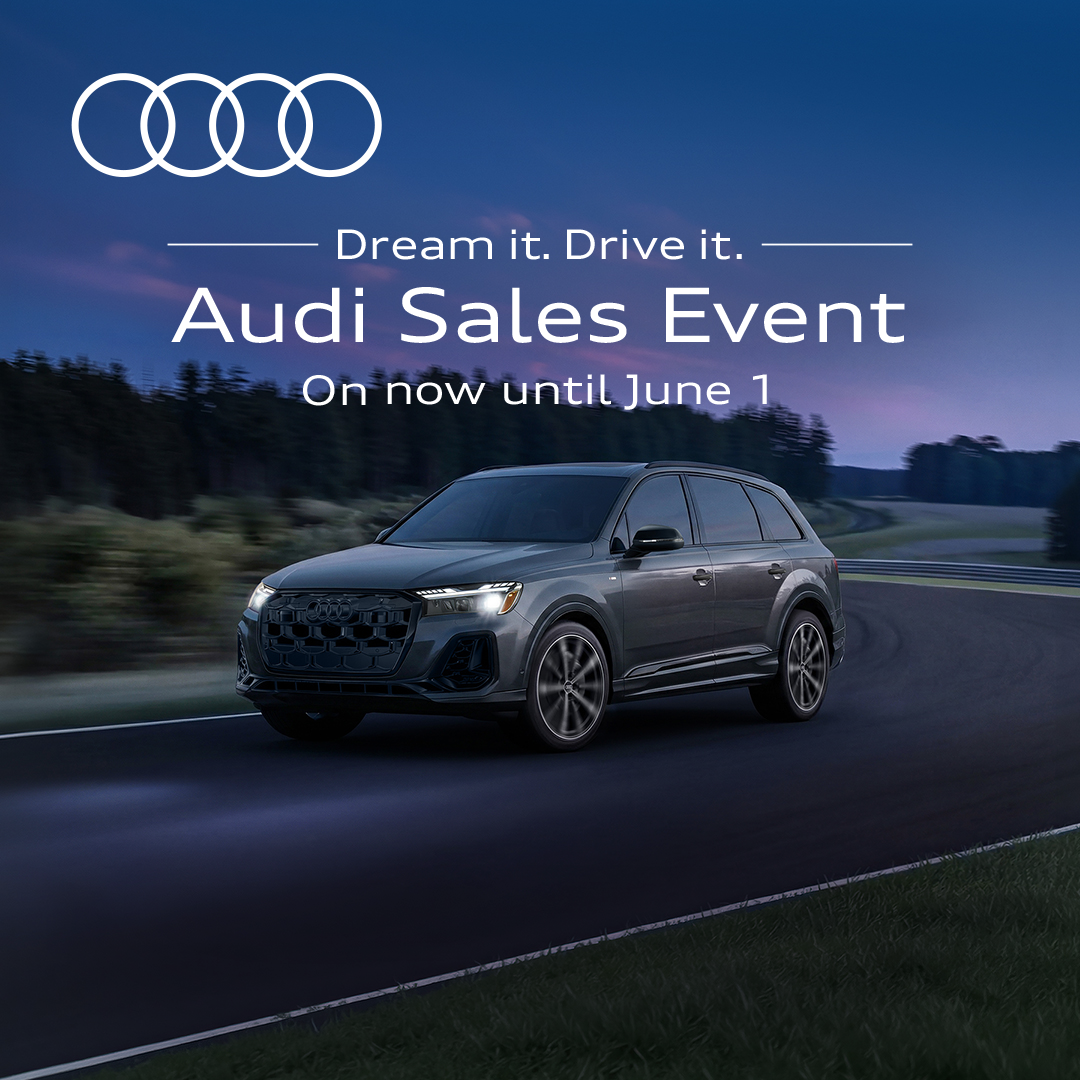 A grey Audi Q5 driving around a track with a pink and purple sky behind it. 